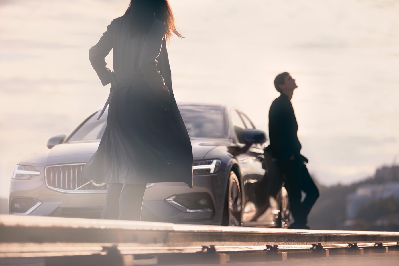 Un couple installé à côté de leur Volvo S60 2021 garé au bord d'un quai
