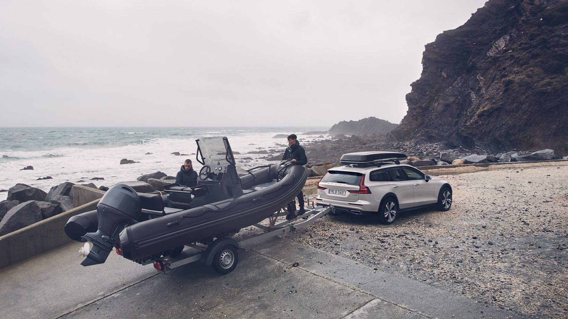 Une Volvo V60 Cross Country 2022 avec un bateau sur sa remorque avec deux amis se préparant à affronter la mer
