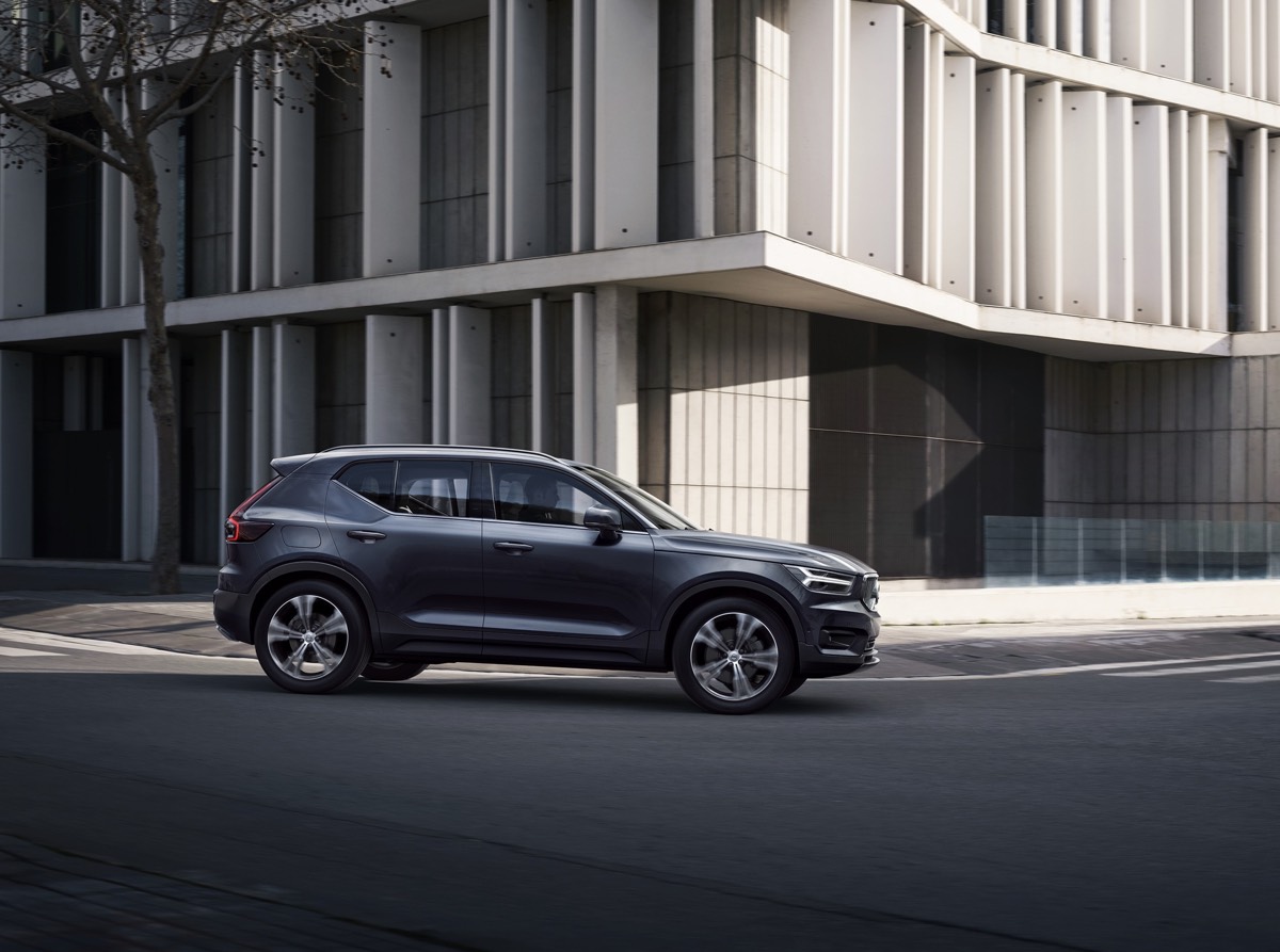 Vue latérale du Volvo XC40 version Inscription Bleu Denim effectuant un tournant sur une rue en ville