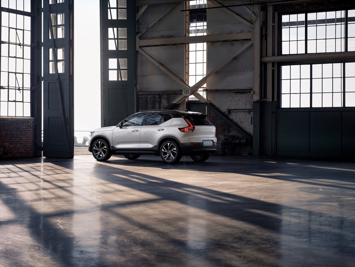 Vue 3/4 arrière du Volvo XC40 R-Design couleur blanc cristal perlé sortant d'un entrepôt