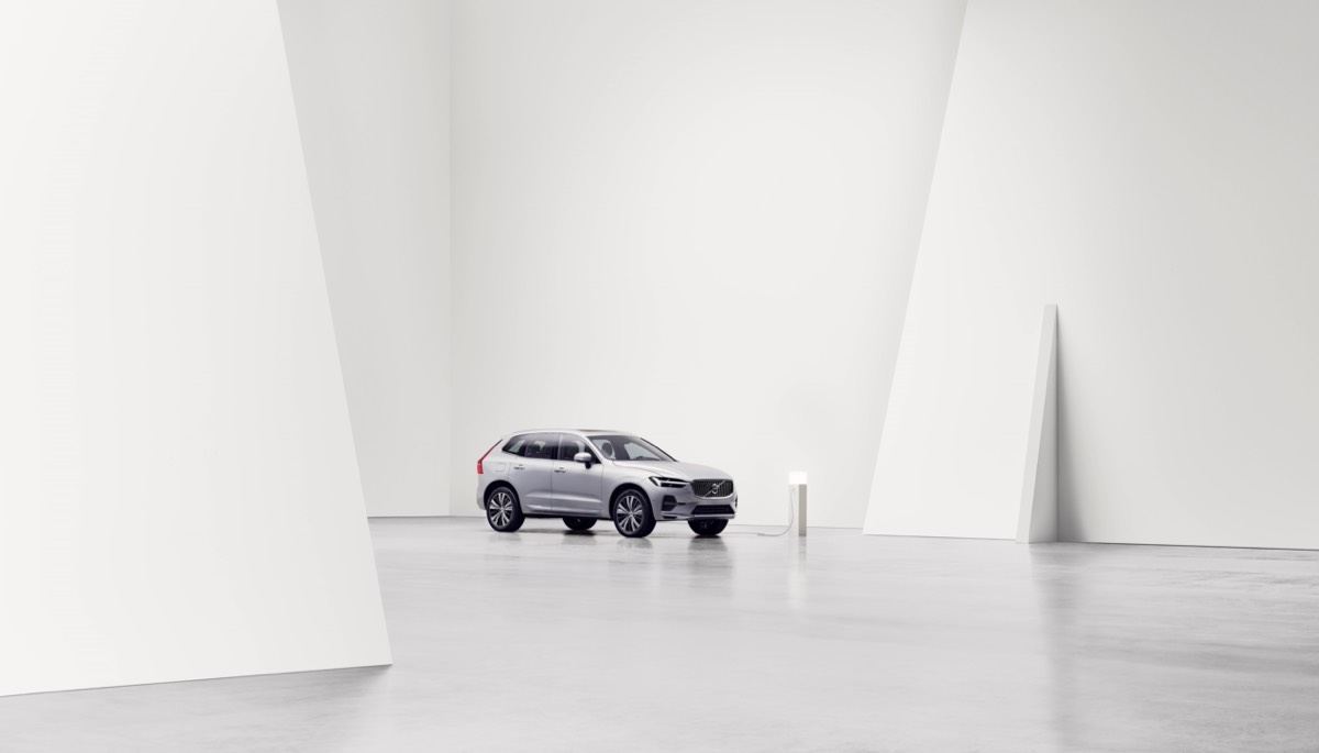 Vue distante du Volvo XC60 électrique 2022 se rechargeant dans une grande pièce blanche