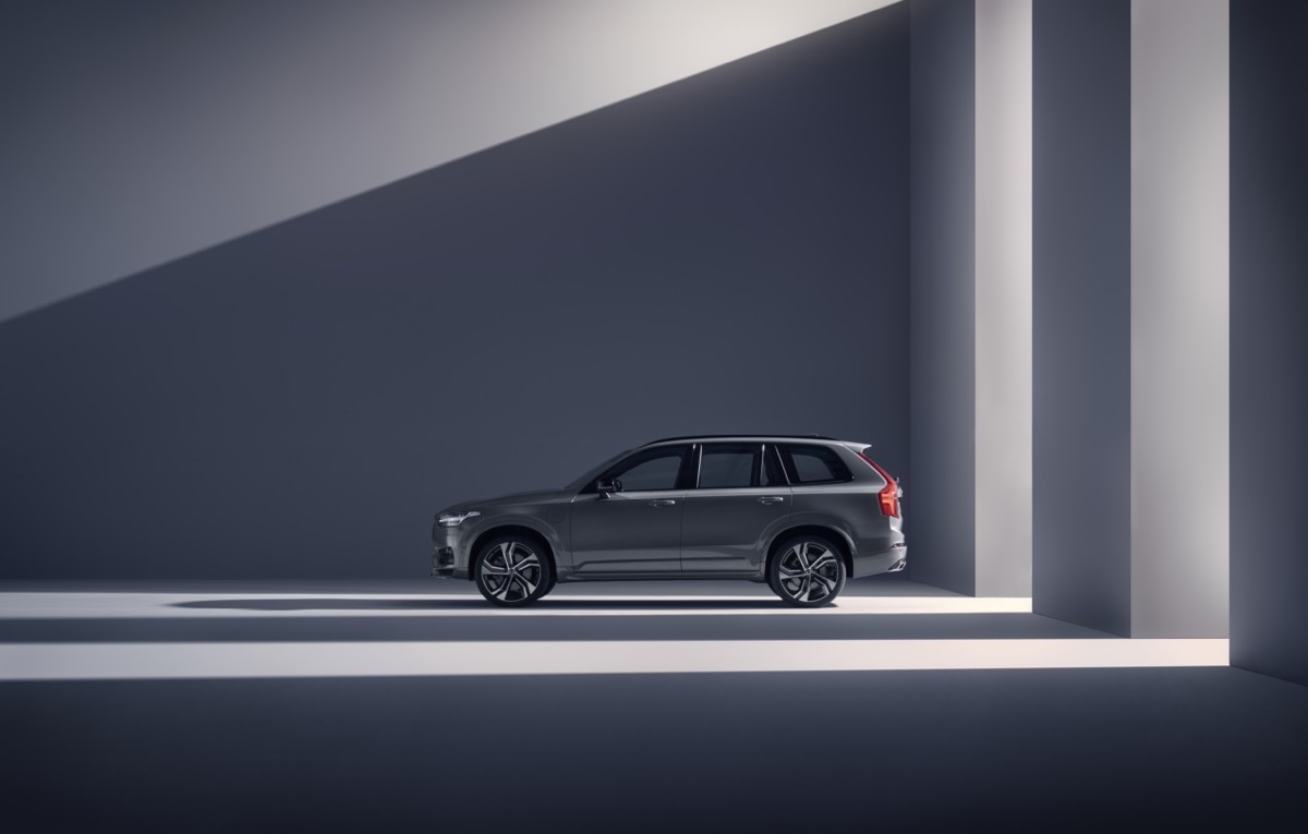 Vue latérale du Volvo XC90 Recharge R-Design gris tonnerre à l'intérieur au reflet de la lumière extérieur