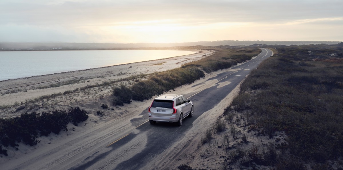 Vue de haut du Volvo XC90 Recharge Inscription roulant sur une route de sable au longeant une plage